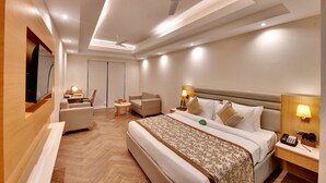 A modern hotel room with a large bed, a desk, a chair, a TV, and a ceiling fan. - Click collection Lucknow (Lucknow)