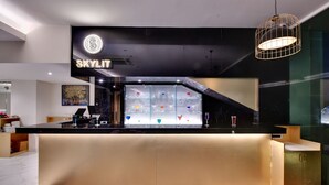 A modern bar area with a black countertop, a glass display case with colorful items, and a sign that reads "SKYLIT". - Click collection Lucknow (Lucknow)