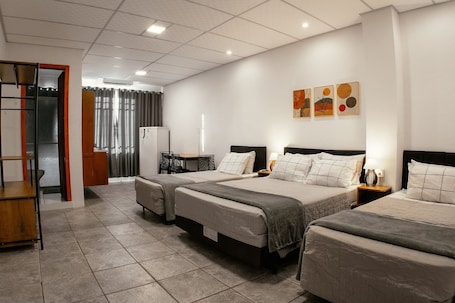 A hotel room with three beds, a wardrobe, a desk, and a window with curtains.. Villa Bilac Studios