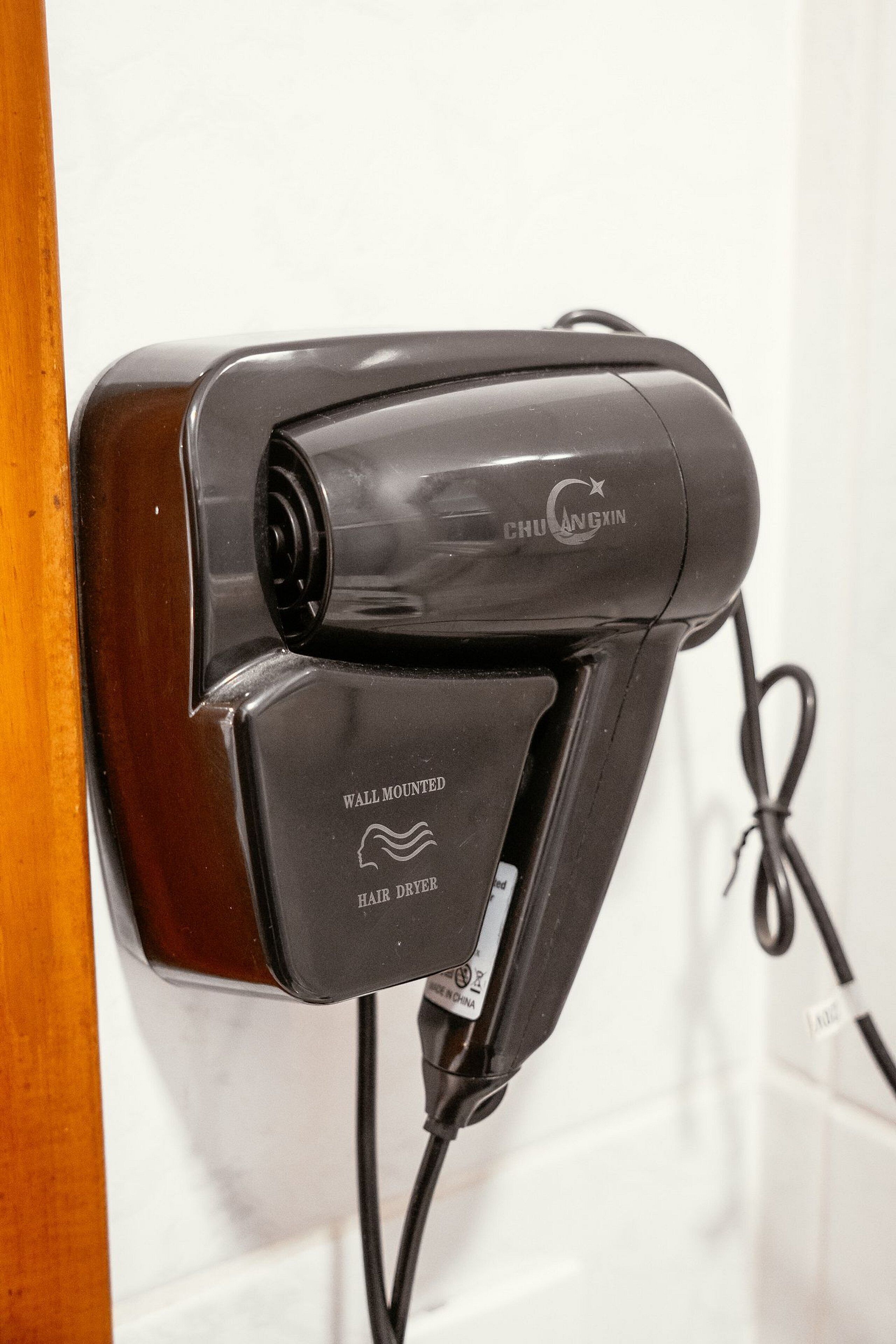 Un secador de pelo fijado a la pared, con cable.