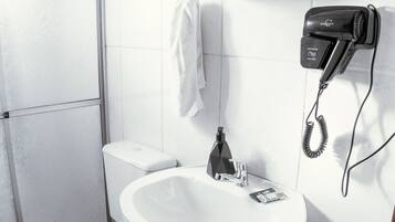 Casa de banho com sanita, lavatório e secador de cabelo.