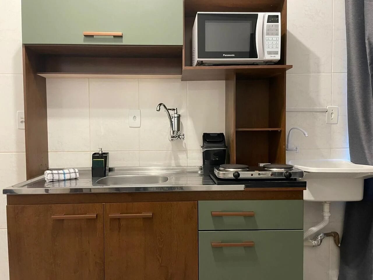 Una cocina compacta con microondas, cafetera y lavabo.