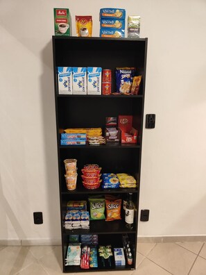 A pantry stocked with various food items including cereal, snacks, and condiments. - Villa Bilac Studios (Blumenau)