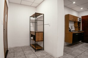Una cocina compacta con un armario de madera, una estantería metálica y suelo de baldosas.