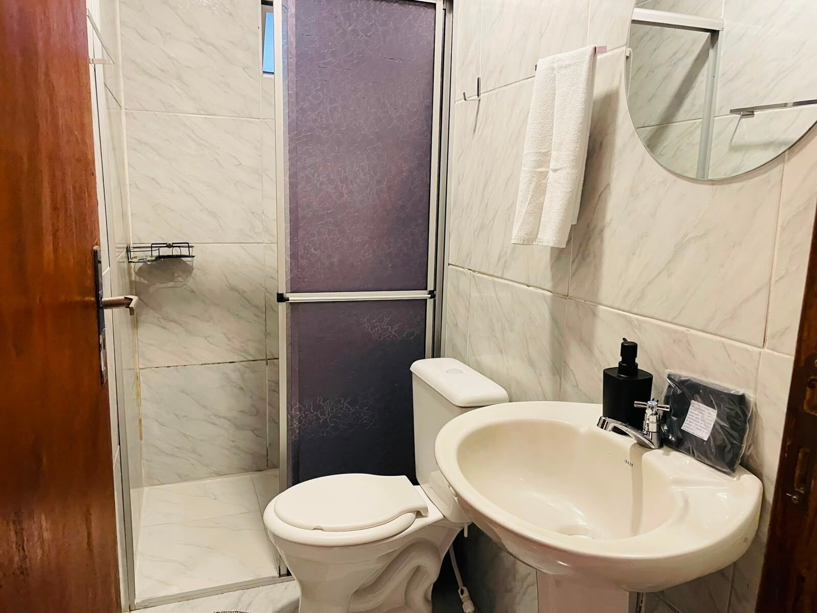 Un baño con inodoro, lavamanos y zona de ducha.