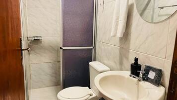 Un baño con inodoro, lavamanos y zona de ducha.