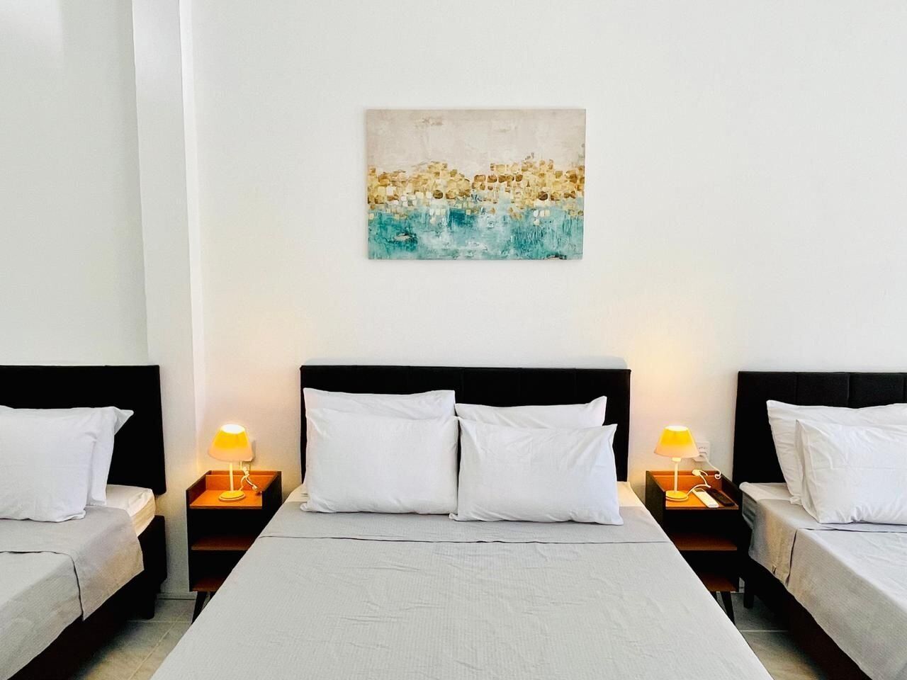 A hotel room with a large bed, two bedside tables with lamps, and a painting on the wall.