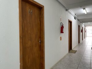 A hallway with wooden doors, a fire extinguisher, and a tiled floor. - Villa Bilac Studios (Blumenau)