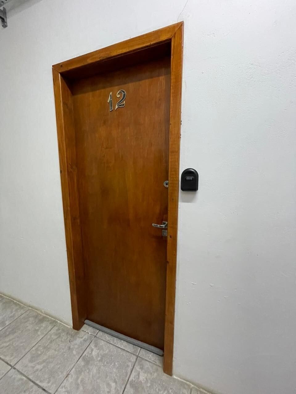 A wooden door with the number 12, a door handle, and a keypad lock on the wall.