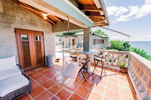 Una terraza con mesa, sillas, un sofá y vista al mar.