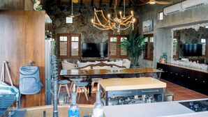 A spacious kitchen with a large island, dining area, stone walls, and a chandelier.