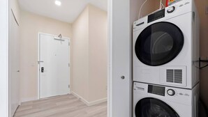 A laundry room with two stacked washing machines, a door, and a light-colored floor. - Fabulous 2BR ! Free Parking !  30 Min to NYC ! (Newark)