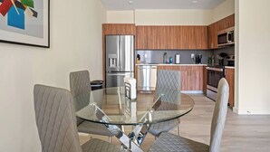 A modern kitchen with wooden cabinets, stainless steel appliances, and a glass dining table with cushioned chairs. - Fabulous 2BR ! Free Parking !  30 Min to NYC ! (Newark)