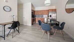 A modern apartment with a dining area, kitchen, and a visible clock on the wall. - Marvelous 2BR ! Free Parking !  30 Min to NYC (Newark)