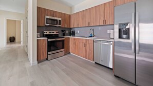 A modern kitchen with wooden cabinets, stainless steel appliances, and a built-in dishwasher. - Marvelous 2BR ! Free Parking !  30 Min to NYC (Newark)