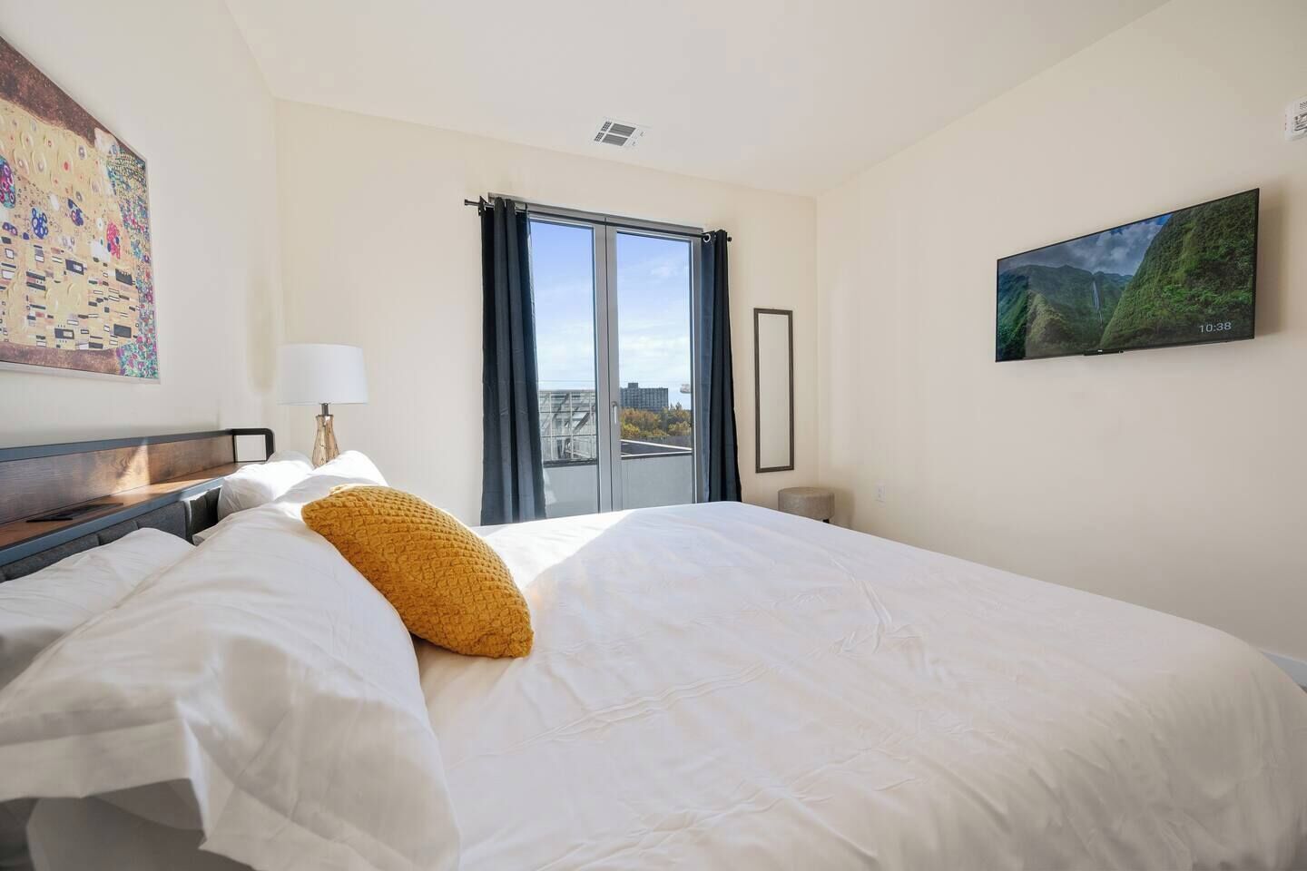 Een hotelkamer met een groot bed, uitzicht over de stad door het raam en een schilderij aan de muur.