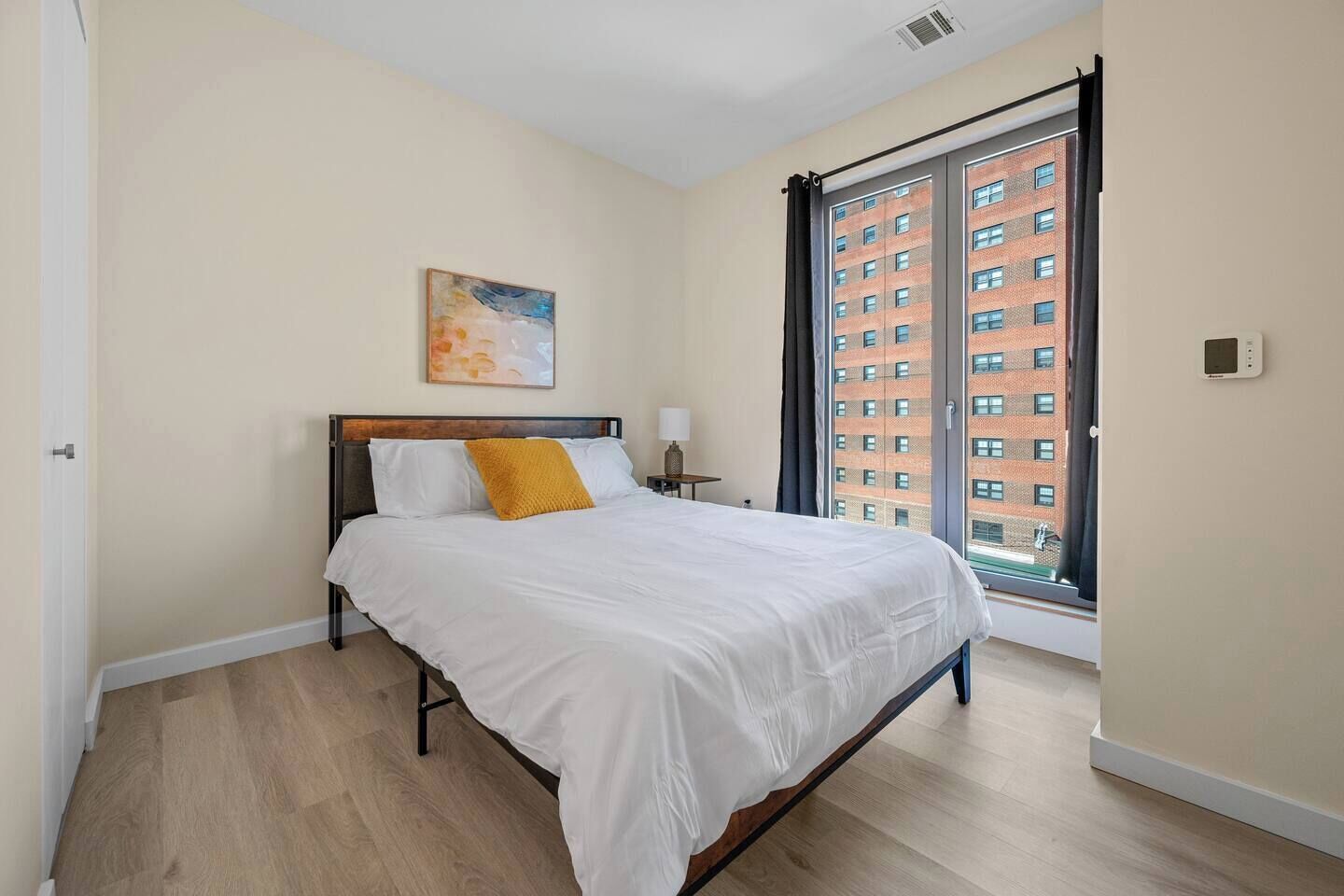 Un dormitorio con cama, ventana y un cuadro en la pared.