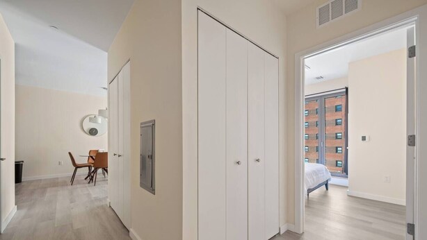 Un appartement moderne doté d’un coin repas, d’une armoire et offrant une vue sur un immeuble en briques.