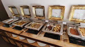 Un buffet con diverse opzioni di cibo, tra cui fagioli al forno, insalata di pasta e altri piatti.