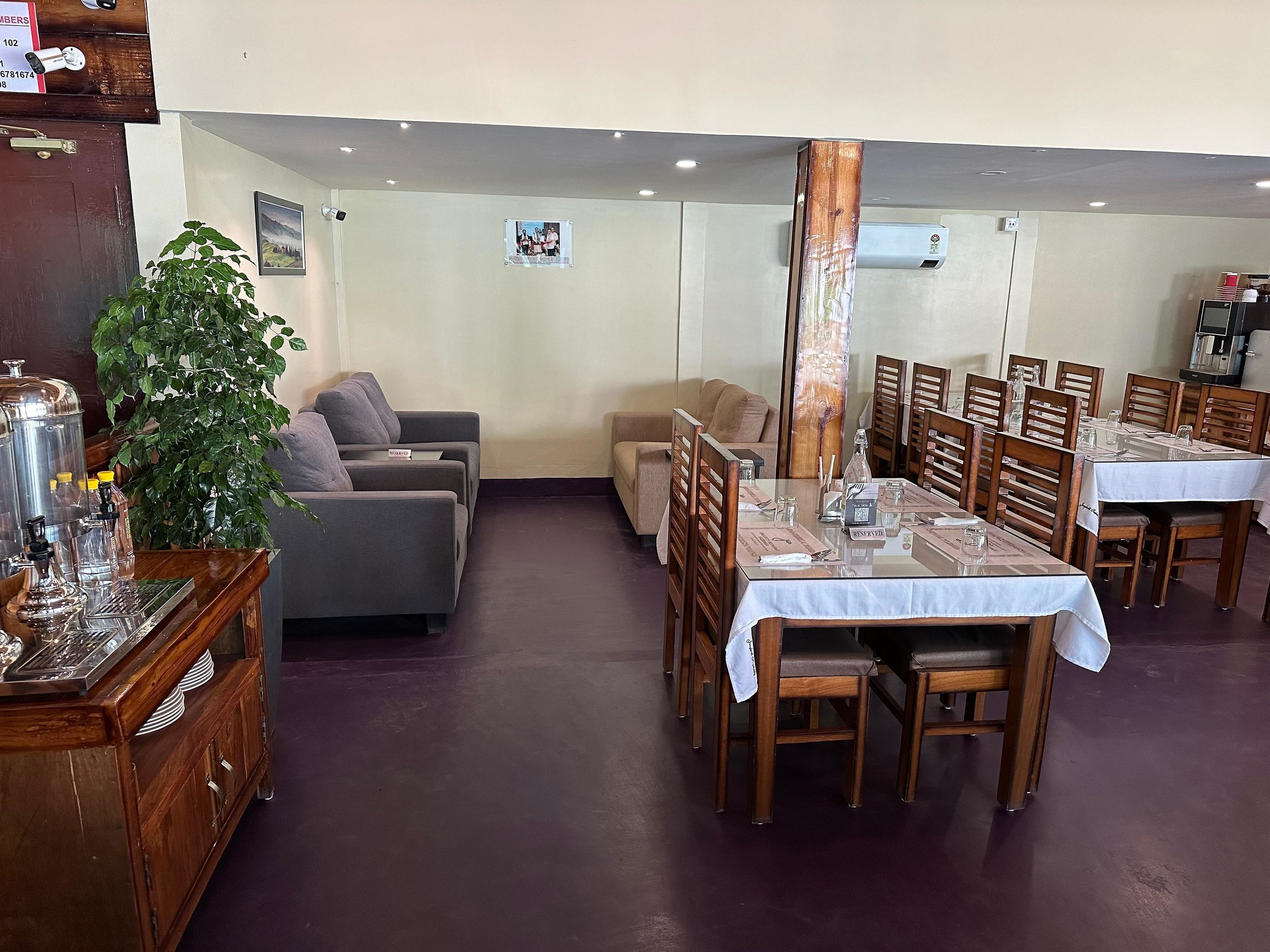 A dining area with a long table, multiple chairs, a sofa, and a coffee machine.