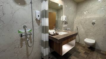 A modern bathroom with a marble floor, a wooden vanity, a sink, a toilet, and a shower area.