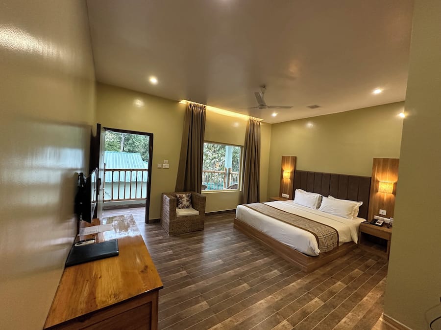 Un dormitorio espacioso con una cama grande, un escritorio de madera y un balcón con vistas.