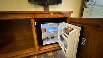 A compact refrigerator with a built-in TV, located under a wooden cabinet in a kitchen area.
