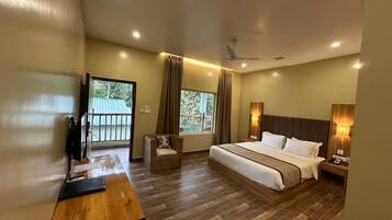 A hotel room with a bed, a desk, a chair, a ceiling fan, and a balcony view.