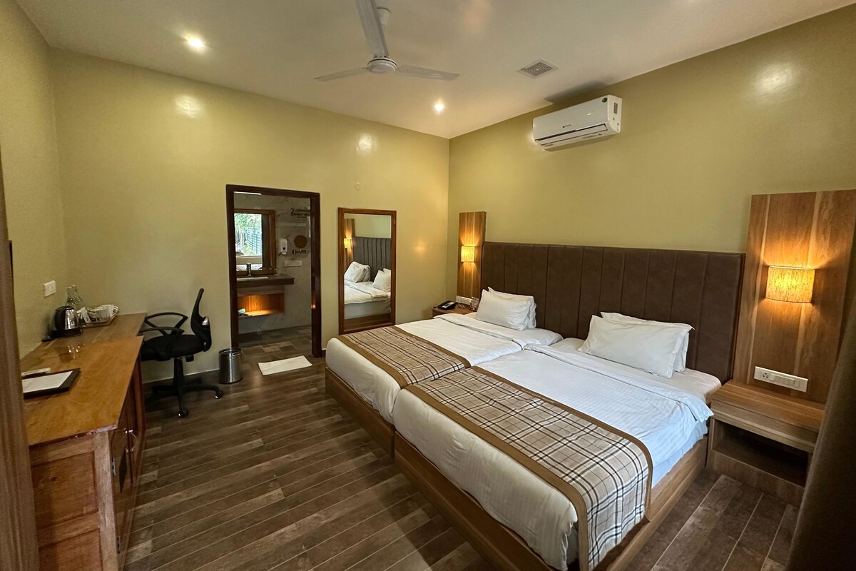 Une chambre d’hôtel avec un grand lit, une tête de lit en bois, des lampes de chevet, un ventilateur de plafond et un appareil de climatisation.