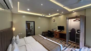 A hotel room with two beds, a desk, a chair, a TV, a wardrobe, and a mirror.