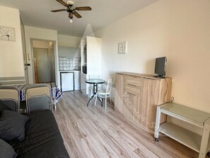 Un espacio habitable compacto con kitchenette, comedor y pequeño escritorio.