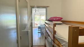 Un couloir étroit menant à un balcon où se trouvent un lit et une table.