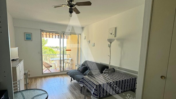 Une petite pièce à aire ouverte comprenant un lit, une table et un ventilateur de plafond.