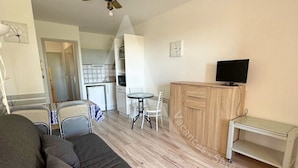 Un salon moderne comprenant un canapé, un téléviseur, un meuble en bois et un coin repas avec des chaises et une table.