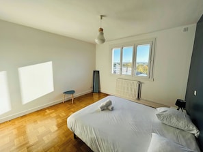 Une chambre à coucher avec un lit, un radiateur, une fenêtre et une chaise.