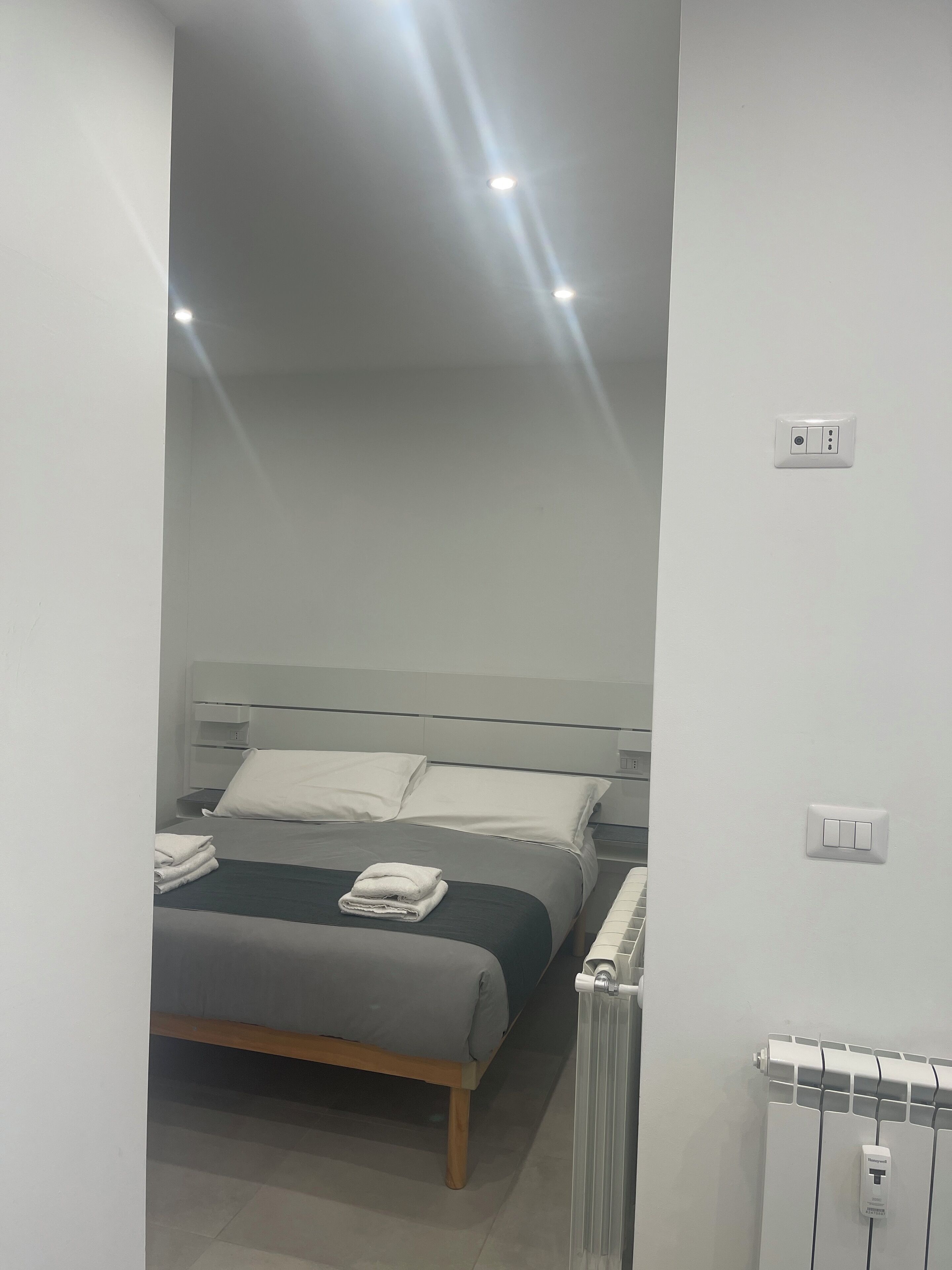 Ein modernes Schlafzimmer mit Bett, Nachttischen und Heizkörper.