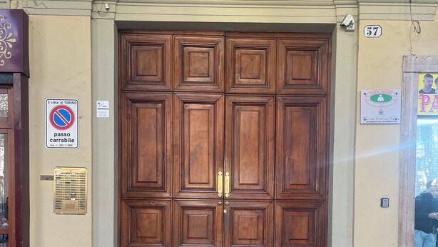 A large wooden double door with a plaque, a no parking sign, and a guest house sign on a building facade. - Porta Nuova Suite 57  (Turin)