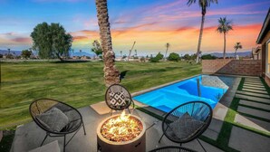A backyard with a swimming pool, two chairs, a fire pit, and palm trees. - Living the DREAM!  Golf and Sunset VIEWS! Brand NEW Home!  Gallery, Indian Palms (Indio)