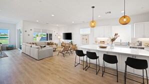 A modern kitchen with a central island, black bar stools, and pendant lighting. - Living the DREAM!  Golf and Sunset VIEWS! Brand NEW Home!  Gallery, Indian Palms (Indio)