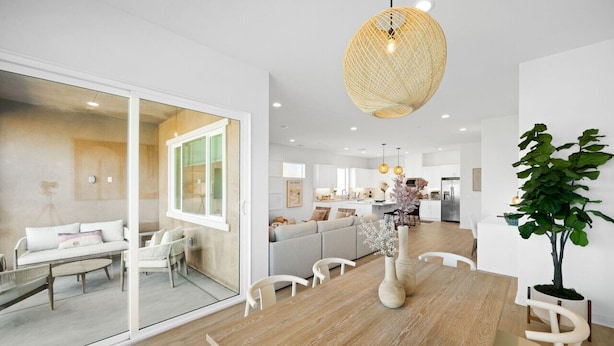 A modern kitchen with white cabinets, a dining area with a wooden table and chairs, and a large potted plant. - Living the DREAM!  Golf and Sunset VIEWS! Brand NEW Home!  Gallery, Indian Palms (Indio)