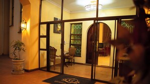 Un hall d’hôtel avec un comptoir d’accueil, une plante en pot et un paillasson portant le nom de l’hôtel.