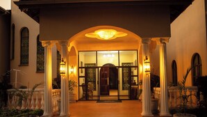 L’entrée d’un hôtel, avec un porche abrité, des colonnes et une porte en verre.