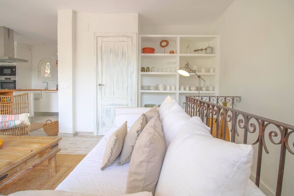 Un salon chaleureux avec un canapé blanc, une table basse en bois et une rambarde en métal.