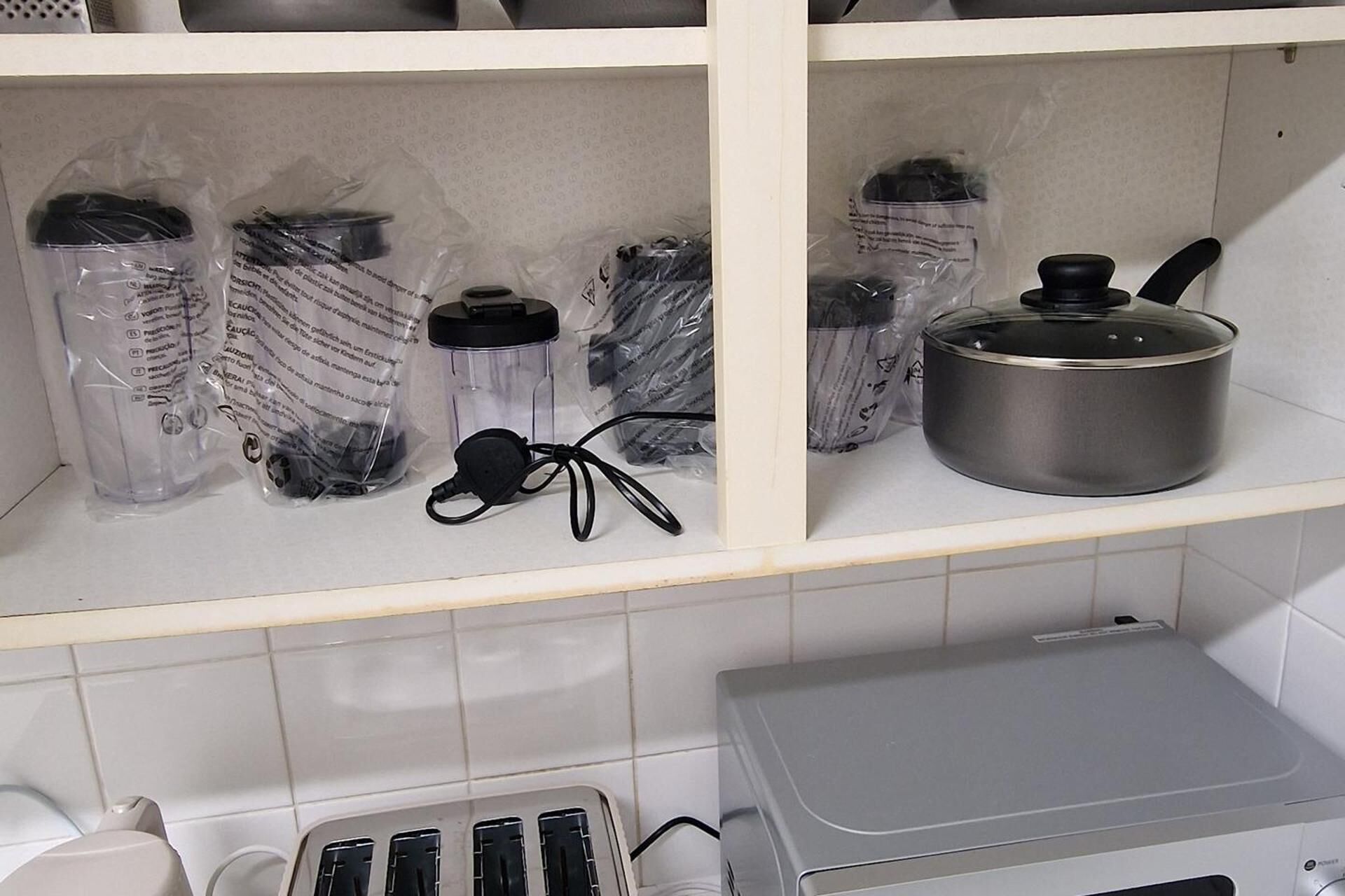 A kitchen shelf with various kitchen items including a kettle, a pot, and a kettle lid.