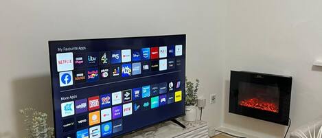 A flat-screen TV on a marble TV stand displaying various app icons.