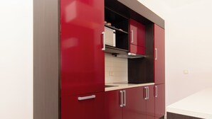 Une cuisine moderne avec des meubles de rangement rouges, une hotte en acier inoxydable et un plan de travail blanc.