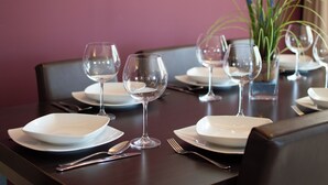Une table à manger dressée avec des assiettes, des verres et des couverts, et un vase rempli de plantes vertes placé sur la table.