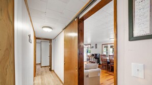 A hallway with wooden flooring leading to a dining area with a table and chairs. - Charming 2-bedroom lakefront cottage in Central Maine with WiFi (Windsor)