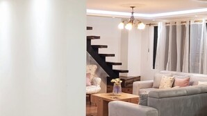 A spacious living area with a grey sofa, a wooden coffee table, and a staircase leading to another level.