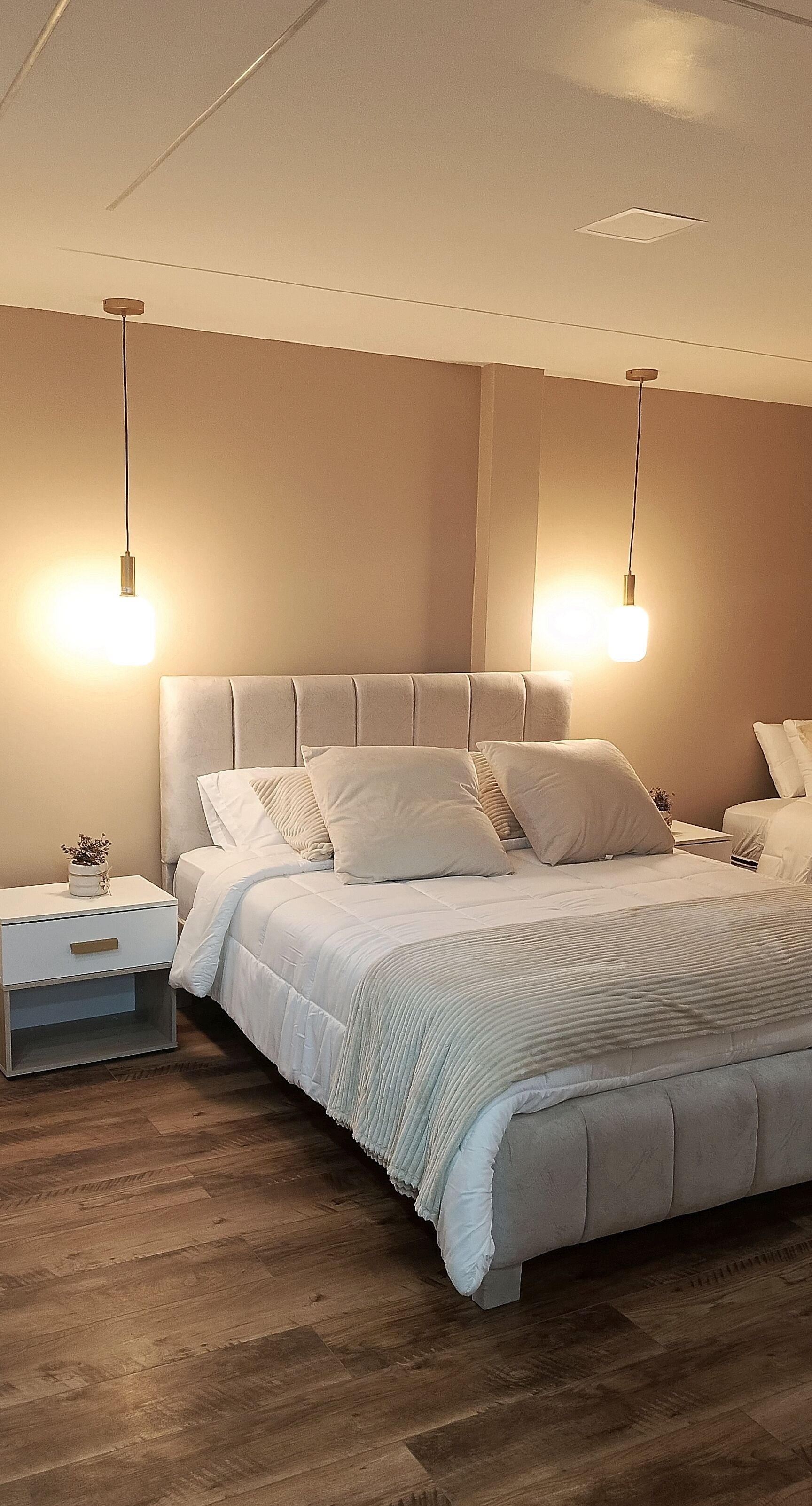 Una camera da letto moderna con un letto grande, due comodini e una lampada a sospensione.
